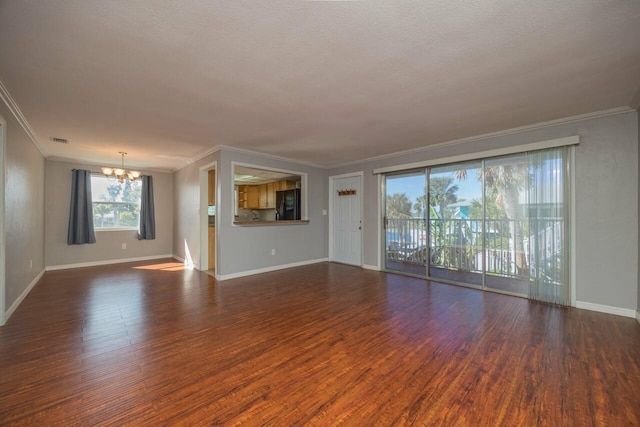 unfurnished living room featuring an inviting chandelier, dark hardwood / wood-style floors, and crown molding