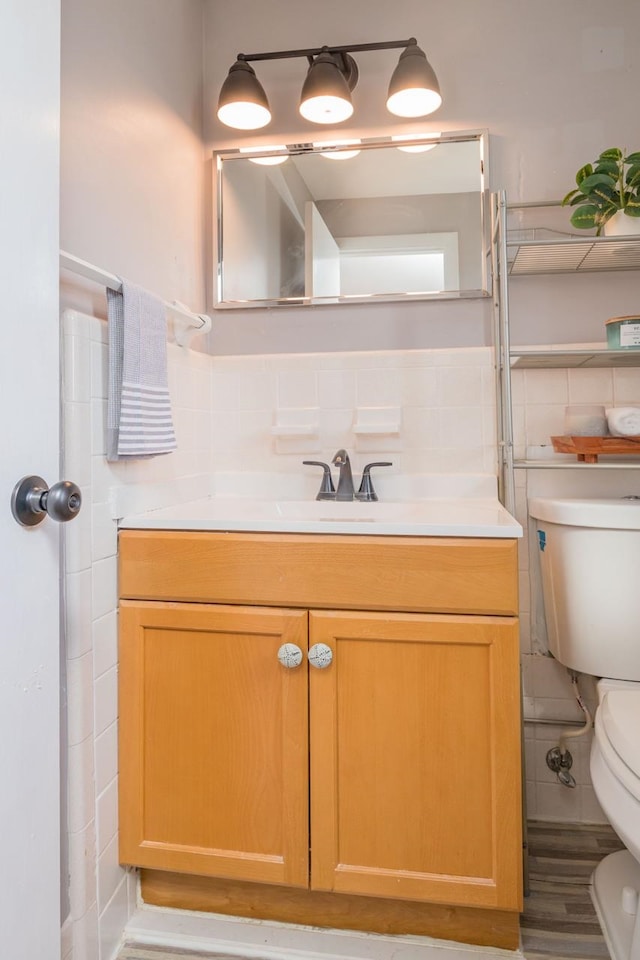 bathroom featuring vanity, tile walls, and toilet