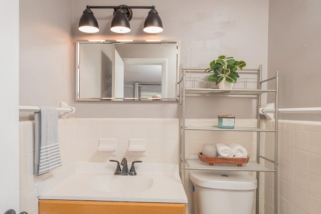 bathroom with vanity, toilet, and tile walls