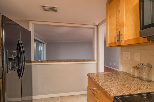 kitchen with tasteful backsplash, range, black refrigerator with ice dispenser, light tile patterned floors, and light stone countertops