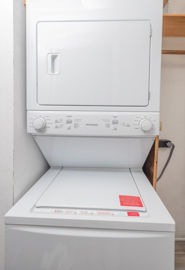 clothes washing area with stacked washing maching and dryer