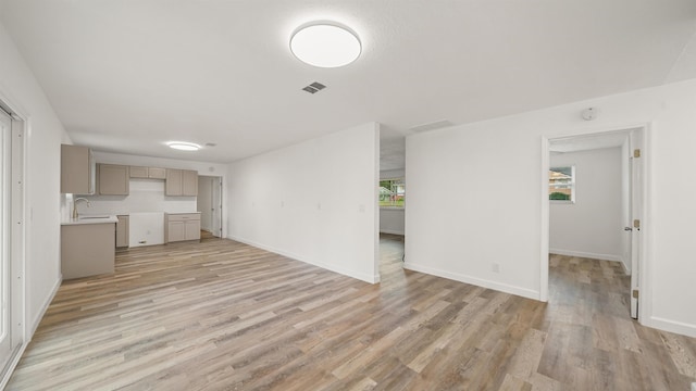 unfurnished living room with light wood-type flooring and sink