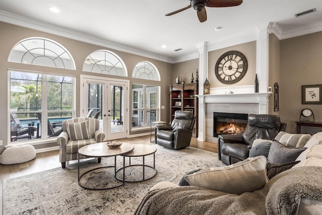 living room featuring a tile fireplace, ornamental molding, wood finished floors, and french doors