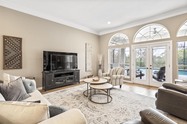 living room featuring light wood finished floors, baseboards, ornamental molding, and french doors