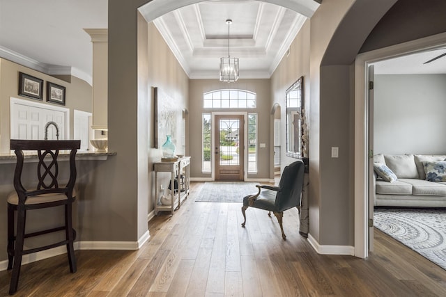 entrance foyer with ornamental molding, a tray ceiling, baseboards, and dark wood-style floors