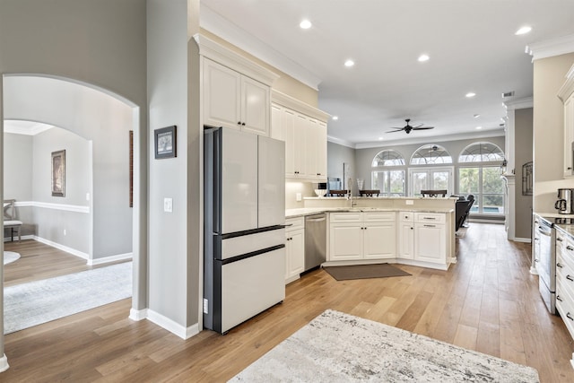 kitchen with a peninsula, appliances with stainless steel finishes, light wood-style flooring, and crown molding