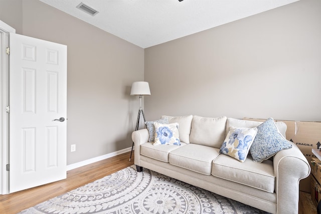 living area featuring wood finished floors, visible vents, and baseboards