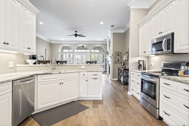 kitchen with ceiling fan, stainless steel appliances, a sink, light wood-style floors, and crown molding