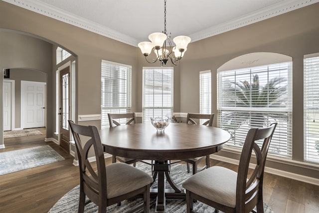 dining space featuring a healthy amount of sunlight, an inviting chandelier, ornamental molding, and wood finished floors