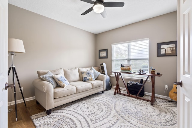 living area with a ceiling fan, baseboards, and wood finished floors