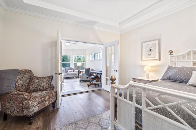 bedroom with ornamental molding, a raised ceiling, wood finished floors, and french doors