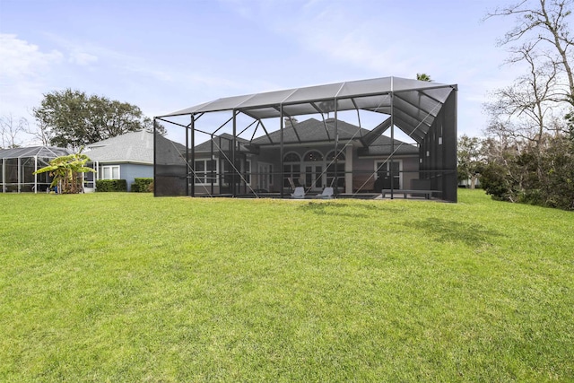 rear view of house with glass enclosure and a lawn