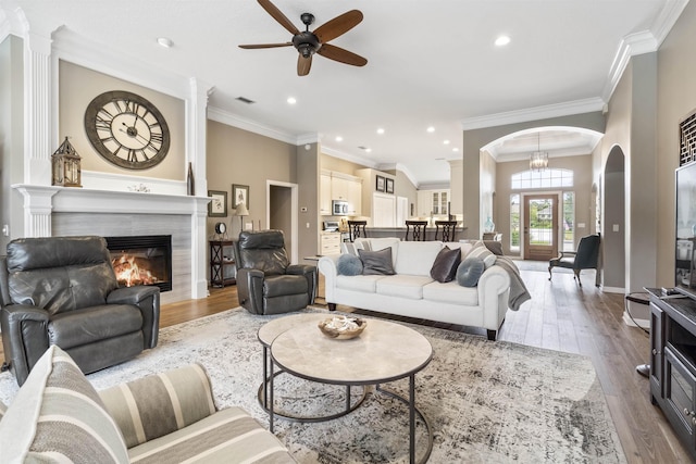 living room featuring arched walkways, a fireplace, recessed lighting, visible vents, and wood finished floors