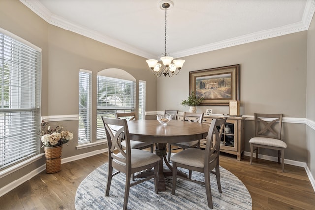 dining room with a notable chandelier, crown molding, wood finished floors, and baseboards