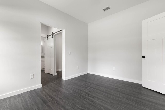 unfurnished room featuring a barn door and dark hardwood / wood-style floors