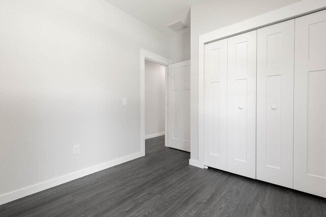 unfurnished bedroom with a closet and dark hardwood / wood-style flooring