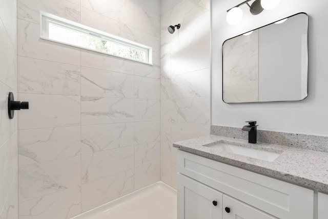 bathroom with tiled shower and vanity