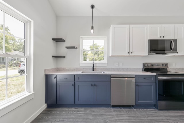 kitchen with hanging light fixtures, white cabinetry, sink, and stainless steel appliances