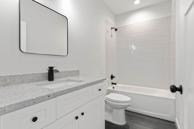 full bathroom with vanity, tiled shower / bath combo, hardwood / wood-style flooring, and toilet