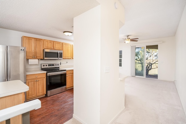 kitchen featuring dark wood-type flooring, ceiling fan, stainless steel appliances, and a textured ceiling