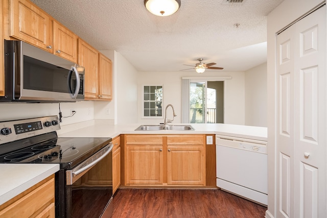 kitchen with sink, a textured ceiling, appliances with stainless steel finishes, dark hardwood / wood-style flooring, and kitchen peninsula