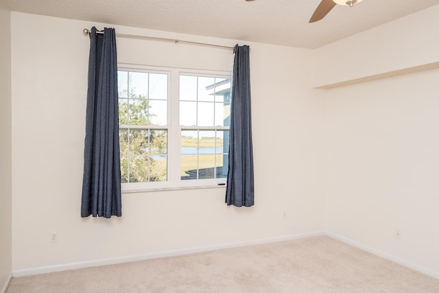 spare room with a water view, ceiling fan, carpet flooring, and a wealth of natural light