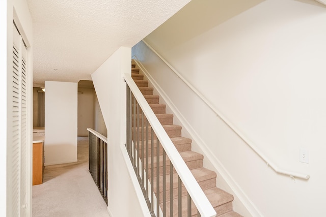 stairs with carpet and a textured ceiling