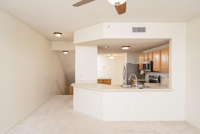 kitchen with appliances with stainless steel finishes, sink, light colored carpet, and kitchen peninsula