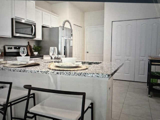 kitchen with white cabinetry, a breakfast bar area, and stainless steel appliances