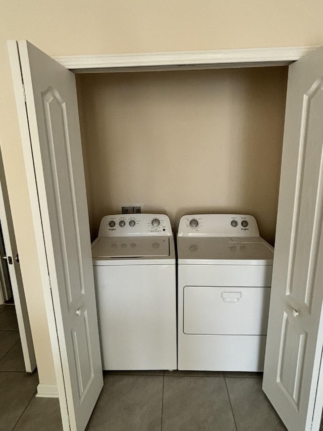 laundry room with washing machine and dryer and dark tile patterned floors