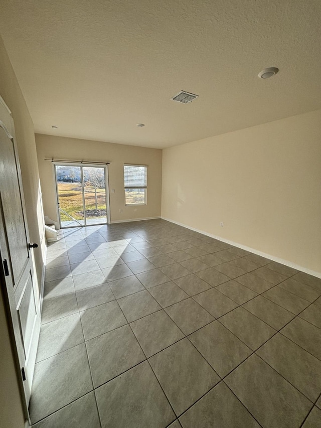 tiled spare room featuring a textured ceiling