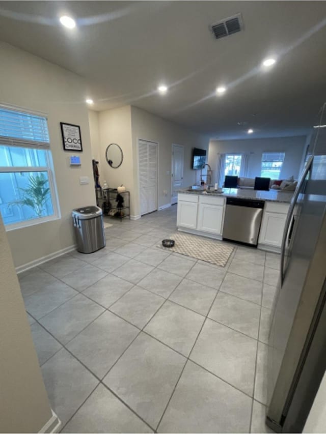 kitchen with light tile patterned flooring, refrigerator, white cabinetry, sink, and stainless steel dishwasher