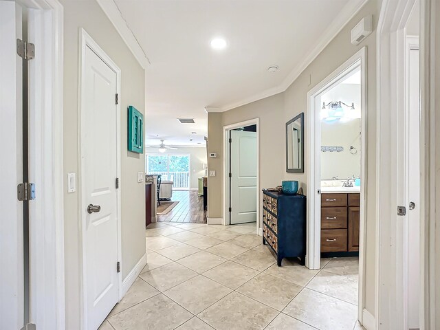 hallway featuring light tile patterned floors and crown molding