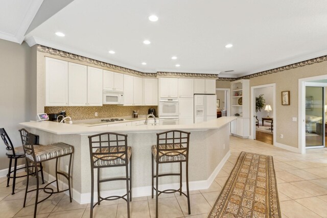 613 Wild Bird Ln, Saint Augustine, FL 32080 - kitchen featuring white appliances, a peninsula, a kitchen breakfast bar, crown molding, and decorative backsplash