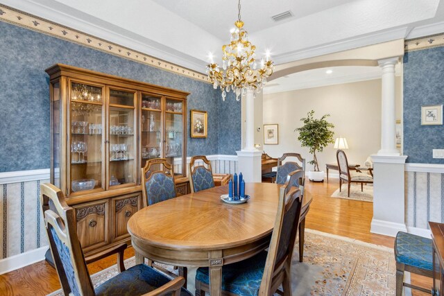 613 Wild Bird Ln, Saint Augustine, FL 32080 - dining space featuring wallpapered walls, ornate columns, a wainscoted wall, light wood-style flooring, and a chandelier