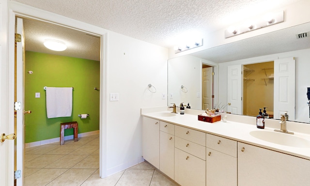 12 Flagler Blvd Unit B201, Saint Augustine, FL 32080 - bathroom with double vanity, tile patterned flooring, a textured ceiling, baseboards, and a walk in closet