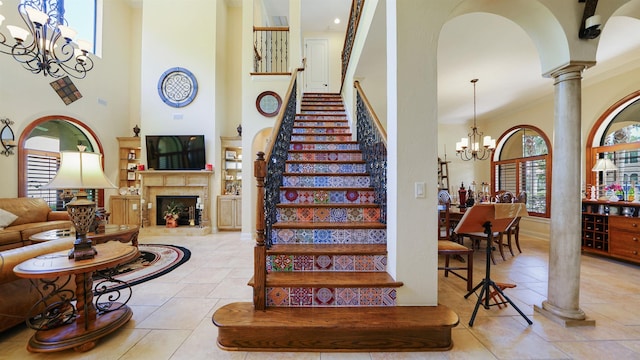 84 Villa Sovana Ct, Saint Johns, FL 32259 - stairs with a chandelier, a high ceiling, decorative columns, a fireplace, and arched walkways