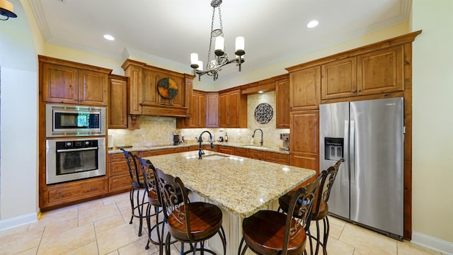 84 Villa Sovana Ct, Saint Johns, FL 32259 - kitchen featuring stainless steel appliances, a chandelier, light stone countertops, brown cabinets, and ornamental molding