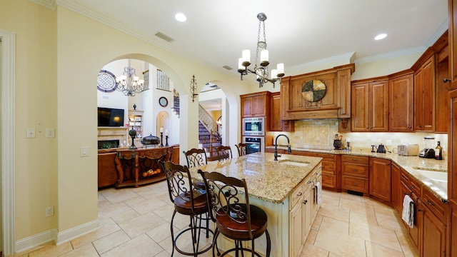 84 Villa Sovana Ct, Saint Johns, FL 32259 - kitchen featuring a chandelier, stainless steel appliances, arched walkways, a kitchen bar, and ornamental molding