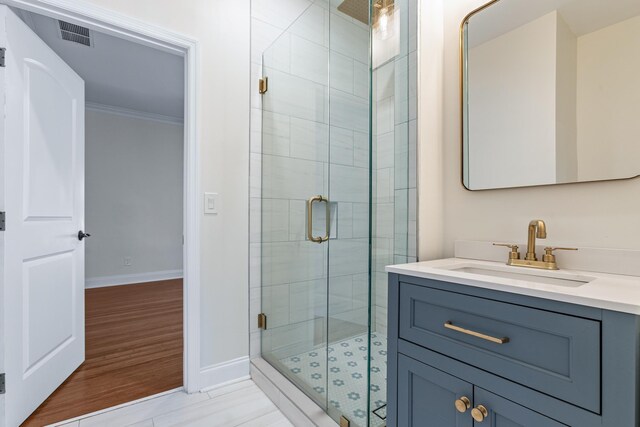 bathroom featuring vanity, a shower with door, wood-type flooring, and crown molding