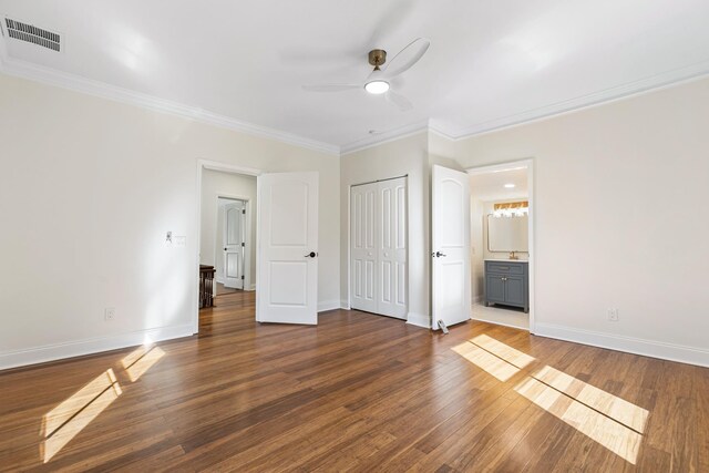 unfurnished bedroom with ceiling fan, dark hardwood / wood-style flooring, crown molding, and connected bathroom