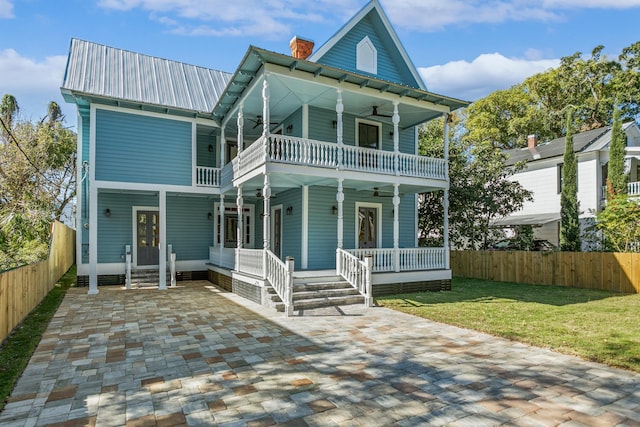 view of front facade featuring a balcony, a front lawn, and covered porch