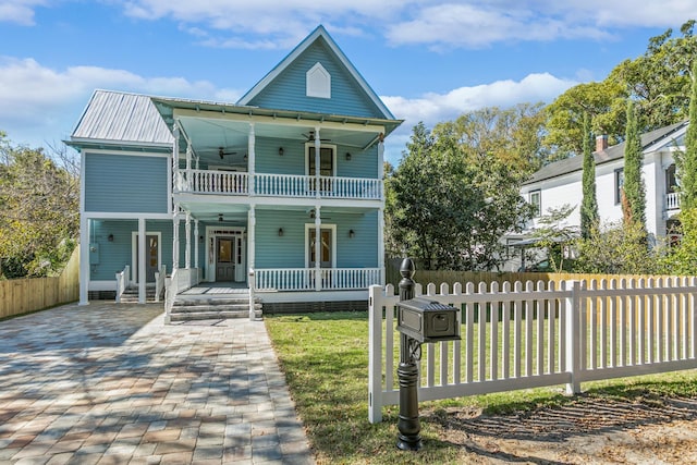 view of front facade with ceiling fan, a porch, a balcony, and a front lawn