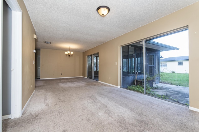 empty room with carpet, a textured ceiling, and an inviting chandelier