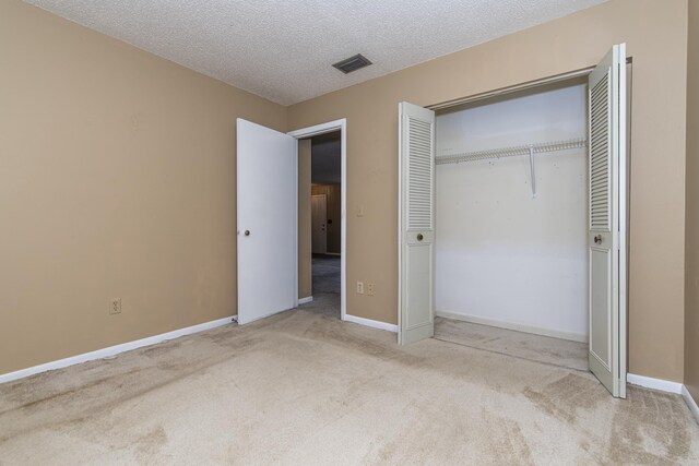 unfurnished bedroom with light carpet, a textured ceiling, and a closet