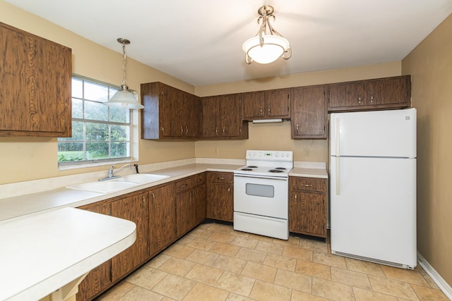 kitchen featuring dark brown cabinetry, sink, hanging light fixtures, and white appliances