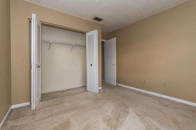 unfurnished bedroom with a textured ceiling, light colored carpet, and a closet