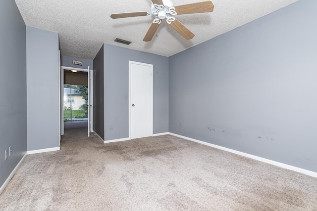 spare room featuring a textured ceiling, light colored carpet, and ceiling fan