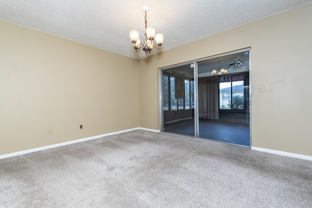 spare room featuring carpet flooring, a textured ceiling, and a notable chandelier