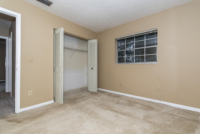 unfurnished bedroom featuring light carpet, a closet, and a textured ceiling